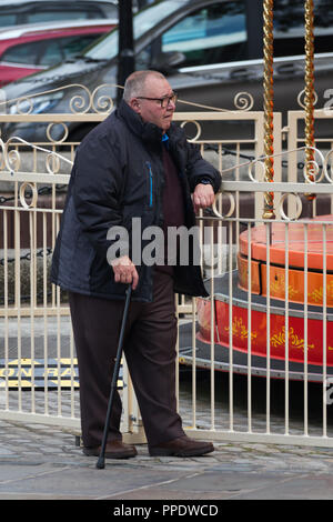 Vieil homme avec un bâton de marche s'appuie contre une balustrade de prendre une pause de la marche. Banque D'Images