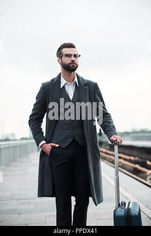 Voyage d'affaires. Young businessman walking near railway avec assurance confiante Banque D'Images