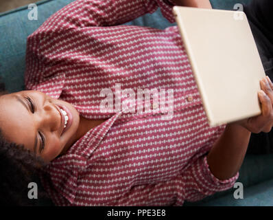 Vue de dessus de Woman Lying On Sofa At Home Watching Movie On Digital Tablet Banque D'Images