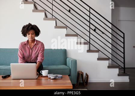 Woman Sitting on Sofa At Home Using laptop computer Banque D'Images