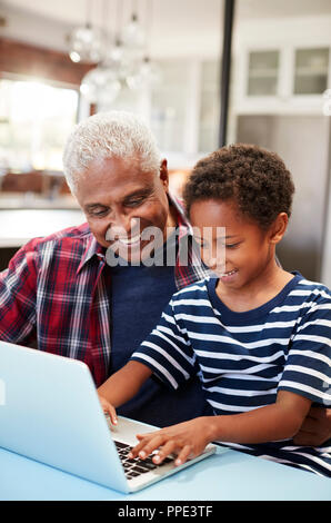 Grand-père et petit-fils assis autour de la table à la maison Using Laptop Together Banque D'Images