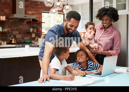 Père aide les enfants à faire leurs devoirs tout en mère détient Baby Banque D'Images