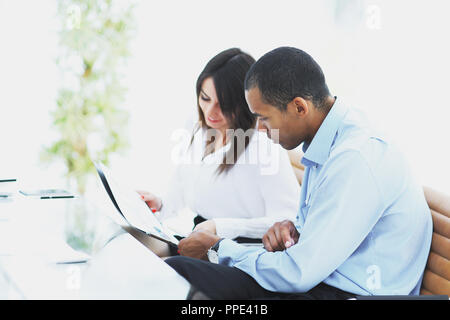 Des collègues des débats sur les documents sitting at Desk Banque D'Images