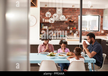 Famille disant Grace Avant repas autour de la table à la maison Banque D'Images