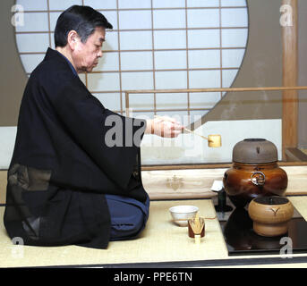 40 ans de japonais de thé au jardin anglais : Maître de thé pendant la Kuramato Soshin cérémonie du thé selon l'École de thé Urasenke du 16ème siècle. Dans le tableau qu'il prend de l'eau chaude à partir de l'urne avec sa louche. Banque D'Images