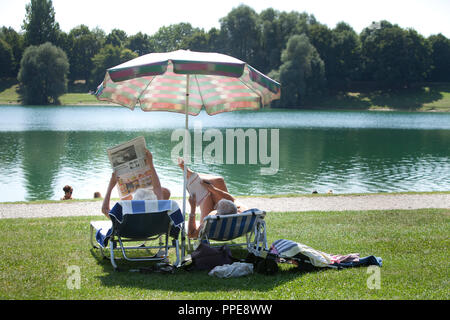 D'âge mûr avec transats et parasol sur la rive du lac Heimstettener. Banque D'Images