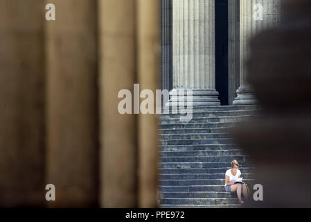 Une femme assise sur les marches en face des colonnes de la Staatliche Antikensammlungen (état des collections d'Antiquités) sur Koenigsplatz à Munich. Banque D'Images