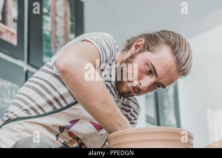 Jeune artiste poterie travaille sur son pot en argile dans un atelier Banque D'Images