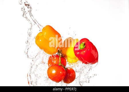 Des poivrons frais et des tomates de l'eau éclaboussant par Banque D'Images