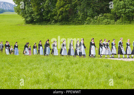 Les femmes en costumes traditionnels - Roeckifrauen - dans la procession du Corpus Christi à travers les plaines et les champs à partir de la colère d'Hoeglwoerth, Bavière, Allemagne, le Saint Sacrement est porté par le prêtre, qui passe sous le 'ciel'. Banque D'Images