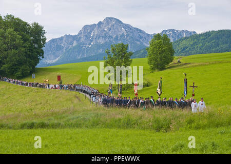 Corpus Christi procession à travers les plaines et les champs de la colère d'Hoeglwoerth avec le Hochstaufen en arrière-plan, la Bavière, l'Allemagne, le Saint Sacrement est porté par le prêtre, qui passe sous le 'ciel'. Banque D'Images