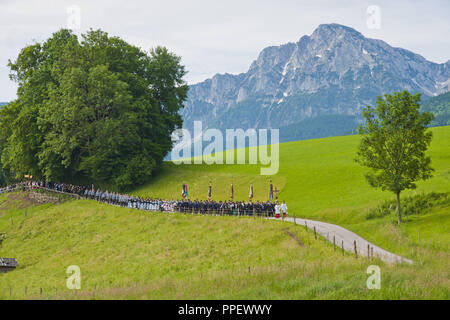 Corpus Christi procession à travers les plaines et les champs de la colère d'Hoeglwoerth avec le Hochstaufen en arrière-plan, la Bavière, l'Allemagne, le Saint Sacrement est porté par le prêtre, qui passe sous le 'ciel'. Banque D'Images