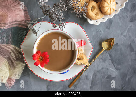 Chocolat chaud le matin dans la tasse blanche originale avec un bouton bleu sur le fond de biscuits. Le petit-déjeuner revigorant Banque D'Images