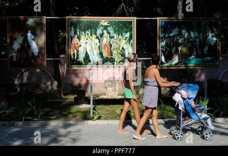 L'Ukraine. République autonome de Crimée. Eupatoria. Les femmes avec une poussette de bébé marchant dans une rue à côté d'une exposition de copies de tableaux célèbres. Banque D'Images