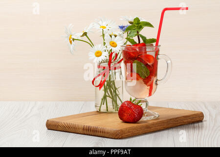 La limonade gazeuse avec des tranches de fraises et de menthe sur une planche à découper en bois, boissons froides pour chaude journée d'été Banque D'Images