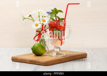 La limonade gazeuse avec des tranches de fraises et de menthe sur une planche à découper en bois, boissons froides pour chaude journée d'été Banque D'Images