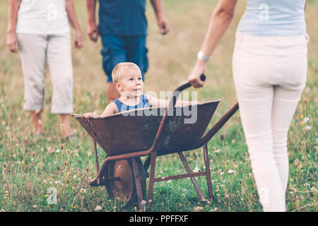 Famille de pousser leurs petits enfants et petits-enfants dans une brouette Banque D'Images