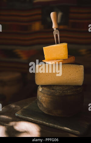 Close-up shot of stacked diverses tranches de fromage avec une fourchette sur une table en bois rustique Banque D'Images