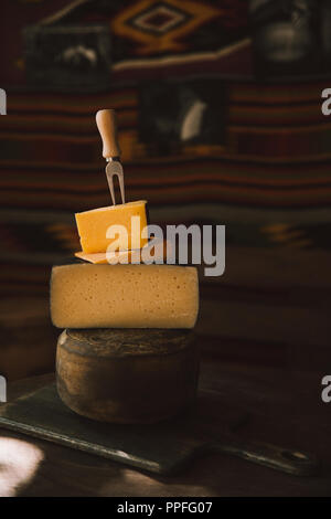 Close-up shot of stacked diverses sortes de tranches de fromage avec une fourchette sur une table en bois rustique Banque D'Images