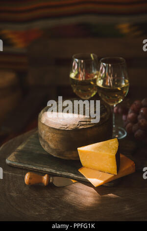 Tranches de fromage délicieux avec du vin et du raisin sur planche à découper en bois Banque D'Images