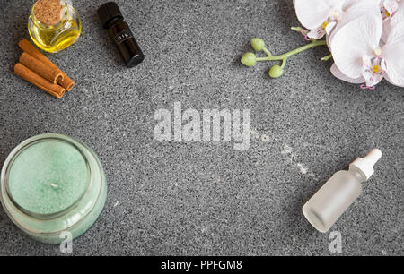 Still Life Spa vue d'en haut avec des bouteilles d'huile, bougie et fleur d'orchidée blanche sur fond de béton Banque D'Images