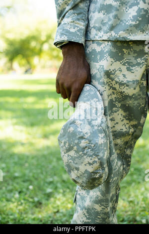 Portrait of african american soldat en uniforme militaire tenue dans le chapeau à la main park Banque D'Images