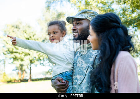 African American fille pointant sur quelque chose au Père en uniforme militaire et de mère en park Banque D'Images