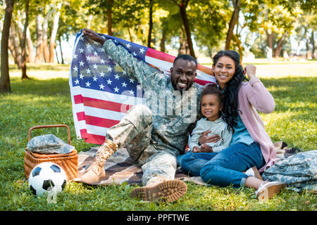 Happy african american soldier en uniforme militaire et family holding american flag in park Banque D'Images