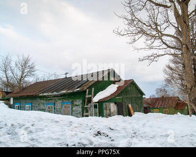 Couverte de neige sur les fenêtres d'une très vieille maison en bois peint en vert dans l'hiver dans l'après-midi Banque D'Images