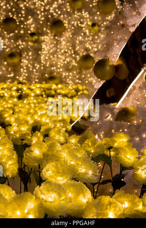 Décoration d'or sur un arbre de Noël avec une lumière jaune fleur. Fleur jaune en vertu de l'arbre de Noël illuminé d'ampoules à LED. Banque D'Images