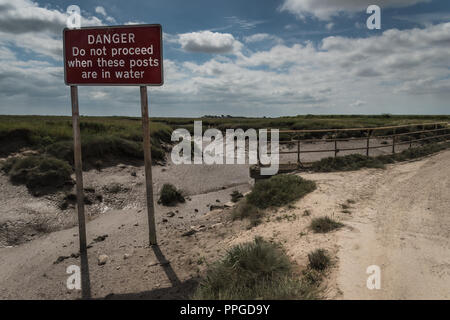 Le village de Lancashire à distance sur un point Sunderland Juin matin à marée basse, England, UK avec tidal road panneau d'avertissement. Banque D'Images