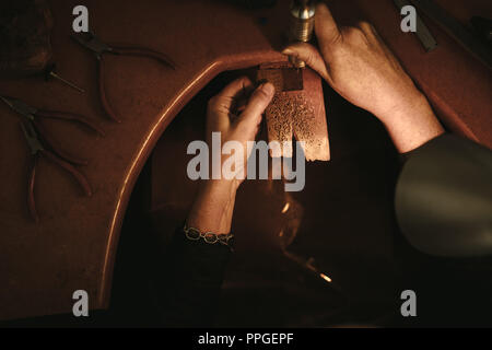 Vue de dessus du bijoutier perçage dans pièce d'or avec la machine. Goldsmith travaillant dans son atelier. POV shot. Banque D'Images