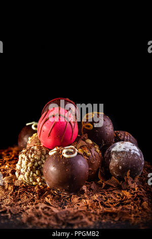 Ensemble d'un assortiment de truffes au chocolat illuminé par l'éclairage créatif, selective focus, fond noir et d'hébergement pour copier l'espace. Banque D'Images