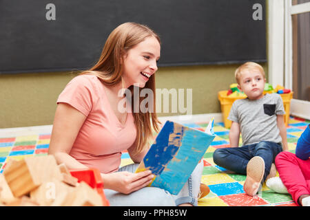 La femme comme un assistant maternel ou de l'éducateur de la maternelle ou une pépinière de lecture Banque D'Images