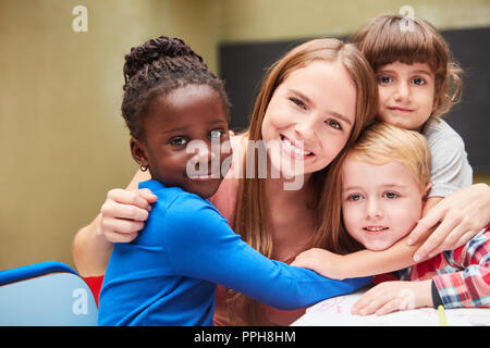 Avec amour enfants embrasser leur enseignant de maternelle à la maternelle ou à la garderie Banque D'Images