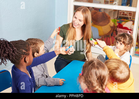 Enseignant de maternelle et groupe d'enfants avec la pâte à modeler dans un atelier artisanal en maternelle Banque D'Images