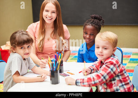 Les enfants et les enseignants de maternelle dans le dessin peinture cours ensemble des photos avec des crayons Banque D'Images