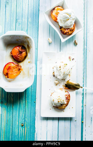 Pêches rôties, de sucre brun et de cannelle, pistacchio, garnie de crème glacée à la vanille Vue supérieure avec éclairage naturel Banque D'Images