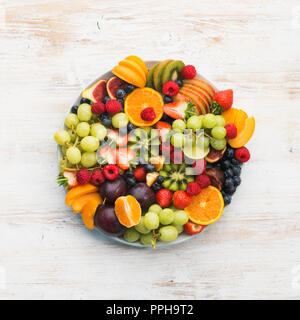 Plateau de fruits sains, Fraises Framboises Pommes Prunes Raisins oranges kiwis bleuets sur la table en bois blanc, haut afficher, copier du texte pour l'espace Banque D'Images