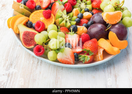 Plateau de fruits sains, Fraises Framboises Pommes Prunes Raisins oranges kiwis bleuets sur la table en bois blanc, copie de l'espace pour texte, selectiv Banque D'Images