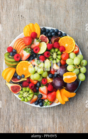 Plateau de fruits sains, Fraises Framboises Pommes Prunes Raisins oranges kiwis bleuets sur la table en bois gris foncé, vertical, vue de dessus, copiez Banque D'Images