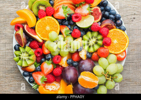 Plateau de fruits sains, Fraises Framboises Pommes Prunes Raisins oranges kiwis bleuets sur la table en bois gris foncé, vue du dessus, Close up Banque D'Images