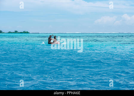 Moorea, Polynésie Française--Mars 18, 2018. Un couple se déplace dans l'eau aqua de la lagune autour de Moorea dans un petit kayak. Banque D'Images