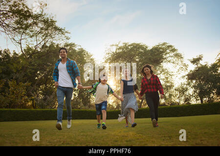 Heureuse famille des homme femme son fils et sa fille walking in park se tenant la main. Banque D'Images