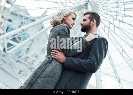 Date romantique en plein air. Young couple hugging parc de divertissement à regarder d'autres passionnés fond voir close-up Banque D'Images