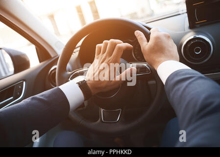 Portrait d'un homme conduisant une voiture avec une main sur un bouton d'avertisseur sonore. Filtre coucher du soleil Banque D'Images