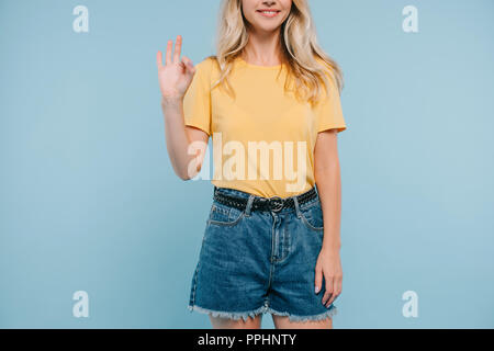 Portrait de jeune fille en chemise et pantalon montrant bon geste isolé sur blue Banque D'Images