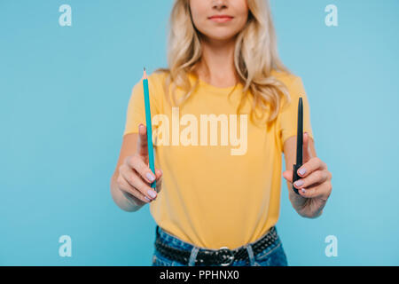 Portrait de jeune fille en maillot et short holding pen and pencil isolé sur blue Banque D'Images