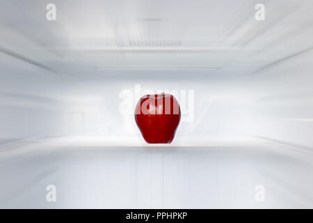 Le dirigeant d'une pomme rouge sur une étagère dans un réfrigérateur vide. Une pomme fraîche dans un réfrigérateur propre vide. Fruits est un refroidissement dans le stockage. Banque D'Images