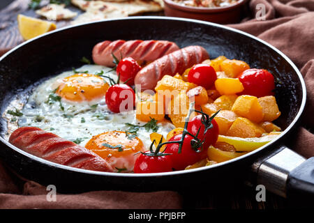 Close up sur une poêle avec de délicieux œufs frits, de délicieux morceaux de citrouille glacé à l', saucisses, tomates rôties, baba ganoush rafraîchir assaisonné de cayenne Banque D'Images